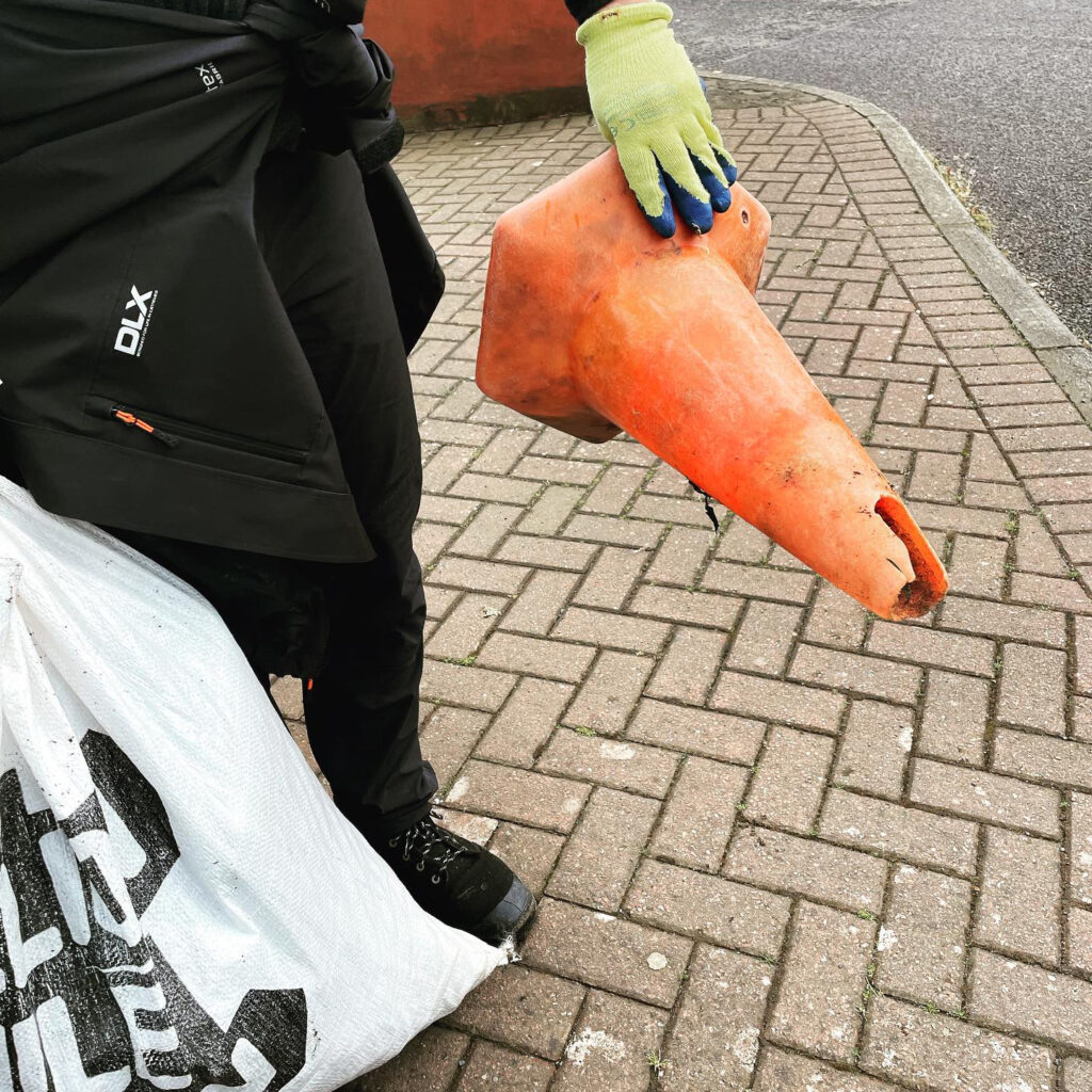 Volunteer holding a traffic cone found during our beach clean.